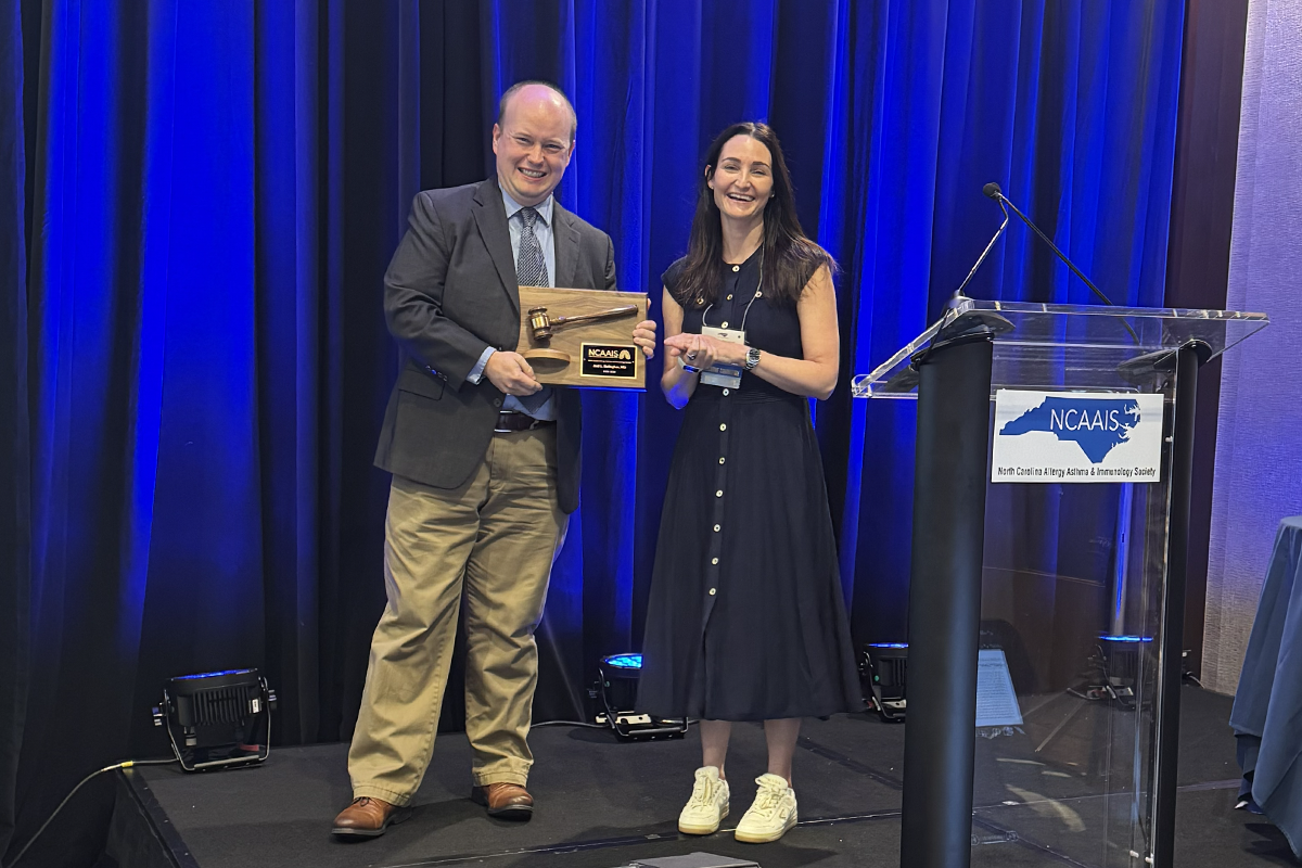Conference room with Dr. Joel Gallagher receiving a plaque for his service in 2025-2026 from incoming president Dr. Erin Dennis